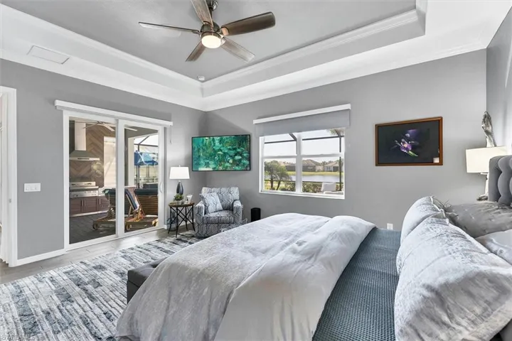 Bedroom featuring access to exterior, hardwood / wood-style flooring, ornamental molding, and a raised ceiling