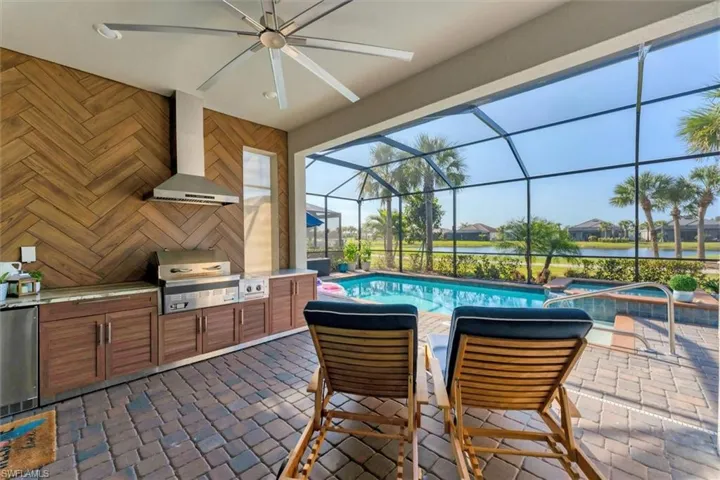 View of patio / terrace featuring a water view, area for grilling, glass enclosure, a pool with hot tub, and a grill