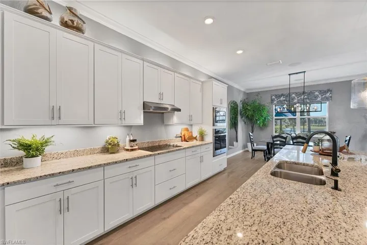 Kitchen featuring pendant lighting, sink, crown molding, stainless steel appliances, and white cabinets