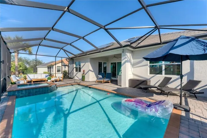 View of swimming pool featuring an in ground hot tub, ceiling fan, a patio area, and glass enclosure