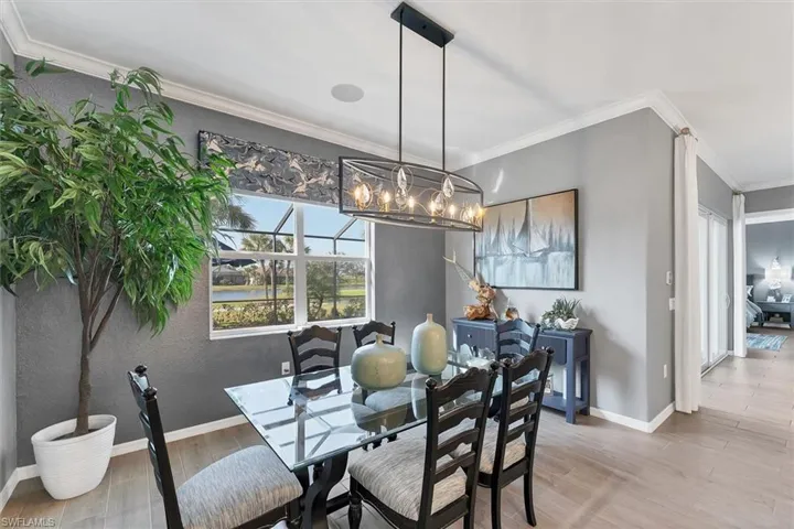 Dining room with hardwood / wood-style flooring, crown molding, and an inviting chandelier