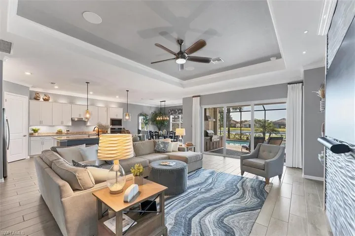 Living room featuring sink, light wood-type flooring, ornamental molding, a raised ceiling, and ceiling fan