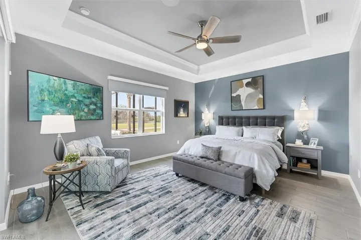 Bedroom with crown molding, ceiling fan, light hardwood / wood-style floors, and a tray ceiling