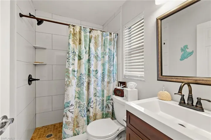 Bathroom featuring vanity, curtained shower, and toilet