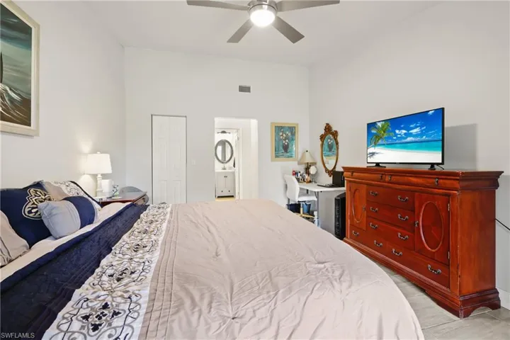 Bedroom featuring ceiling fan, ensuite bathroom, and a closet