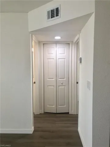 Hallway featuring wood-finish flooring, white walls, and recessed lighting