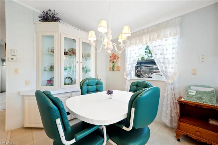 Dining space with light tile patterned floors, an inviting chandelier, crown molding, and lofted ceiling