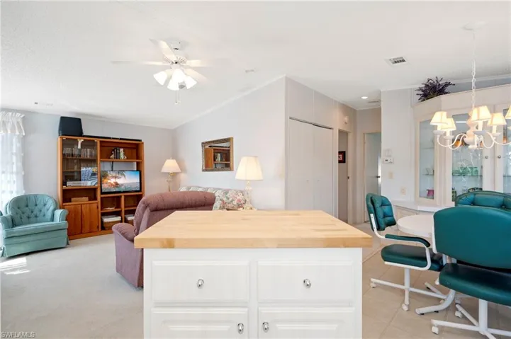 Living Room with a notable chandelier, a closet, vaulted ceiling, crown molding, and visible vents