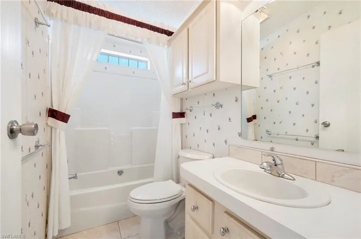 Full bath with tile patterned flooring, vanity, shower / bath combination with curtain, and toilet