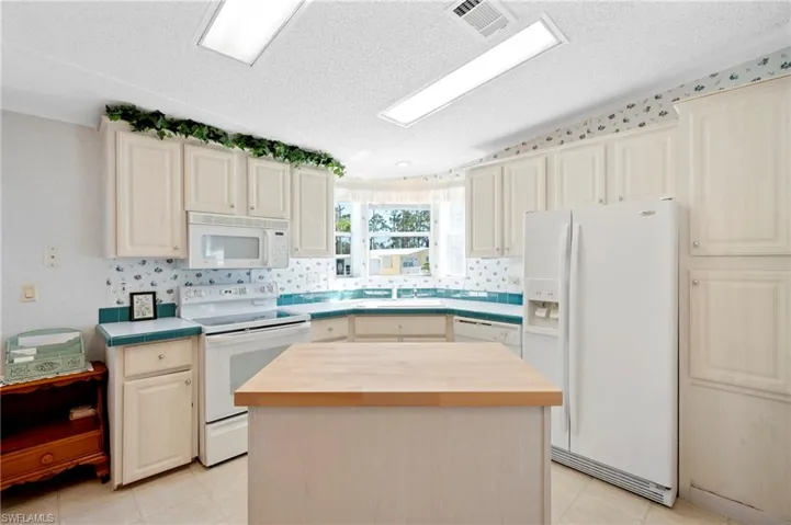 Kitchen featuring a sink, a textured ceiling, white appliances, and butcher block counters