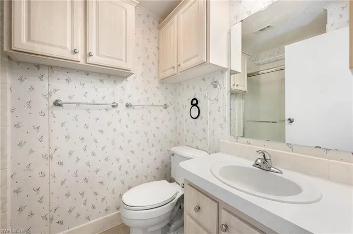 Full bath featuring toilet, an enclosed shower, wallpapered walls, and visible vents