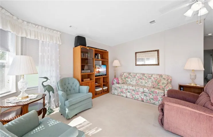 Living room with visible vents, a ceiling fan, and carpet flooring