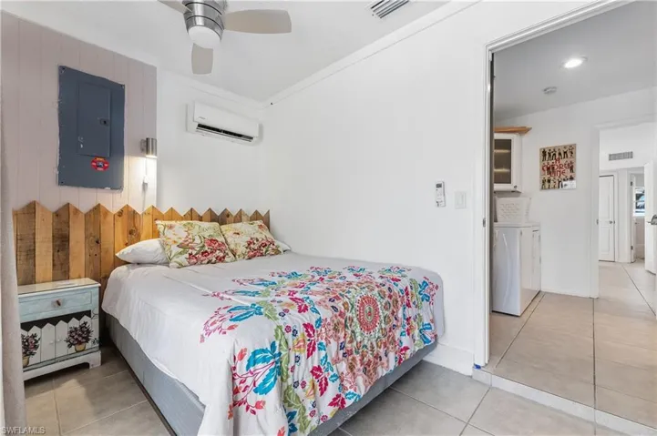 Bedroom with light tile patterned flooring, electric panel, ceiling fan, washer / dryer, and ornamental molding