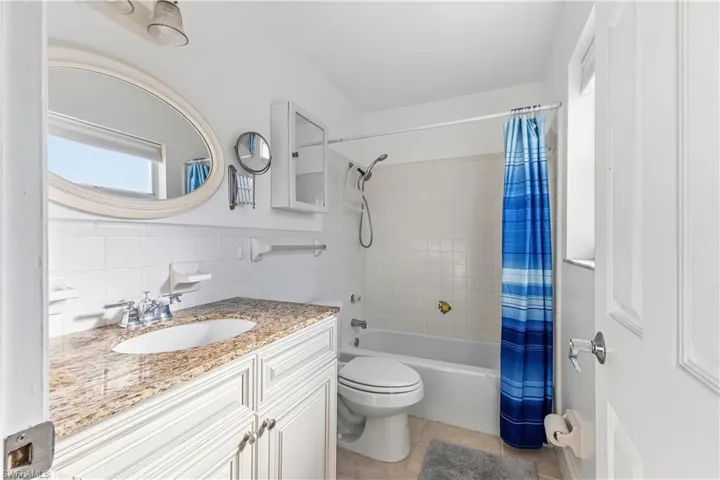 Full bathroom with vanity, shower / tub combo with curtain, light tile patterned flooring, and tile walls