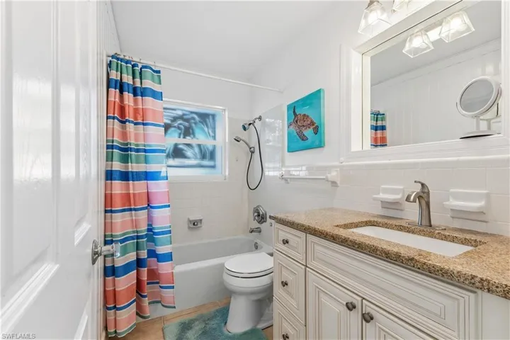 Full bath featuring vanity, shower / bath combination with curtain, light tile patterned floors, and tile walls