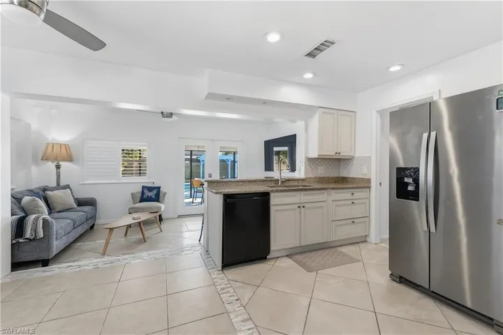 Kitchen with stainless steel refrigerator with ice dispenser, light tile patterned flooring, open floor plan, french doors, and decorative backsplash