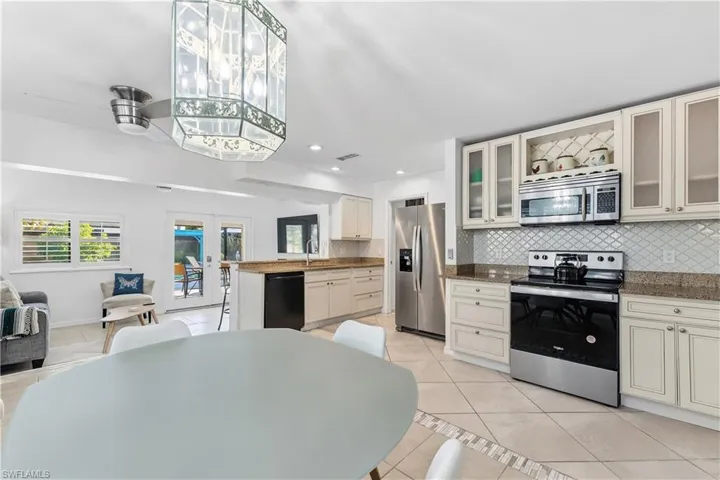 Kitchen featuring appliances with stainless steel finishes, french doors, light tile patterned floors, open floor plan, and backsplash