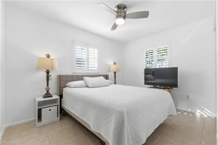 Bedroom featuring multiple windows, light tile patterned floors, and ceiling fan