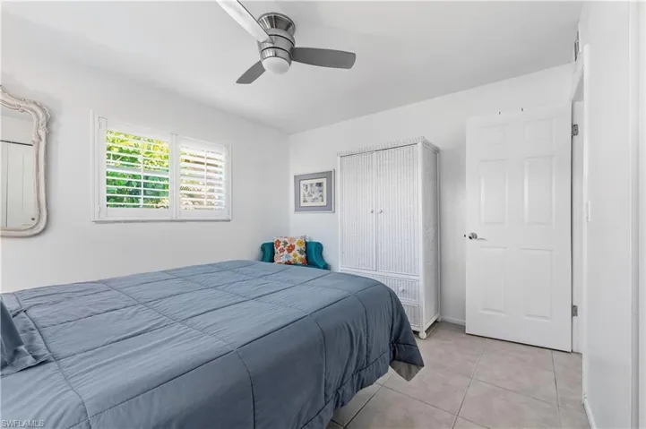 Tiled bedroom featuring ceiling fan and baseboards