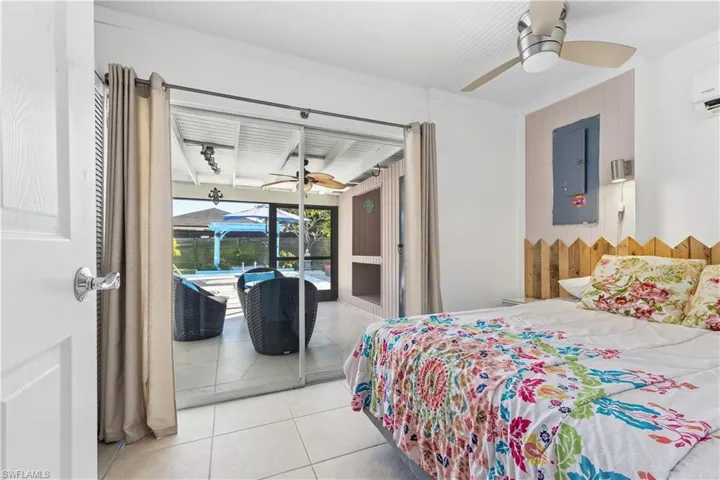 Bedroom with access to outside, a sunroom, tile patterned floors, a ceiling fan, and electric panel