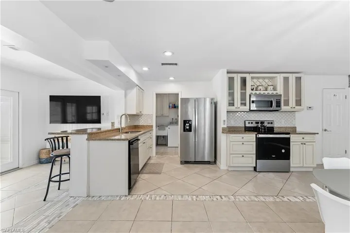 Kitchen with stainless steel appliances, a kitchen bar, a peninsula, tasteful backsplash, and dark stone counters