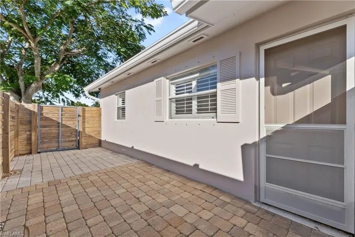 View of side of property with stucco siding, a gate, and a patio area
