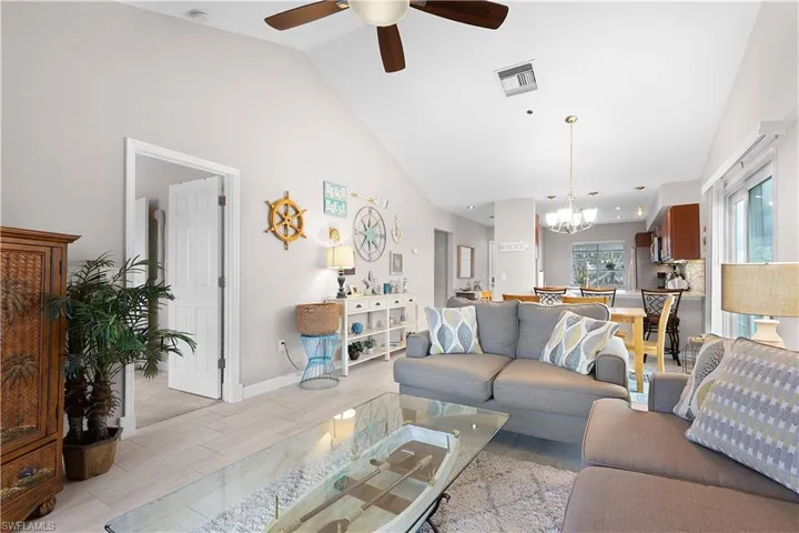 Living room featuring light wood-style flooring, a ceiling fan, a chandelier, and high vaulted ceiling