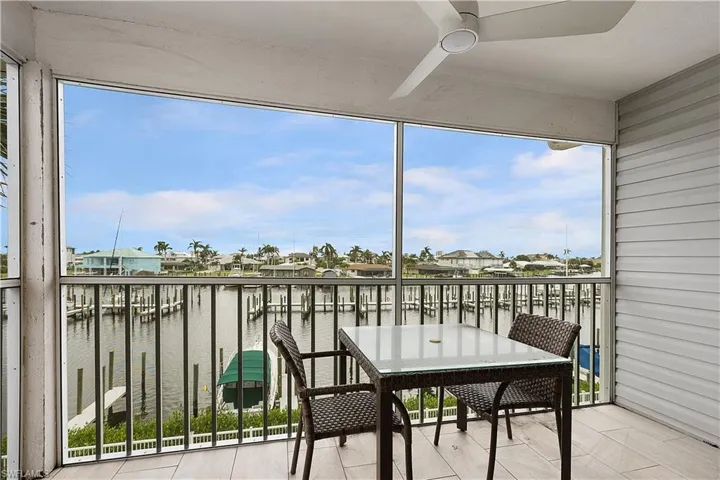 Balcony with a sunroom, a water view, a residential view, and ceiling fan