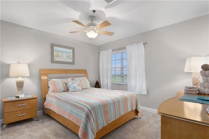 Carpeted bedroom with a ceiling fan and baseboards