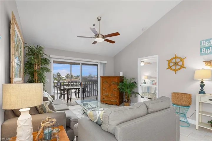 Living room with ceiling fan, wood finished floors, and high vaulted ceiling