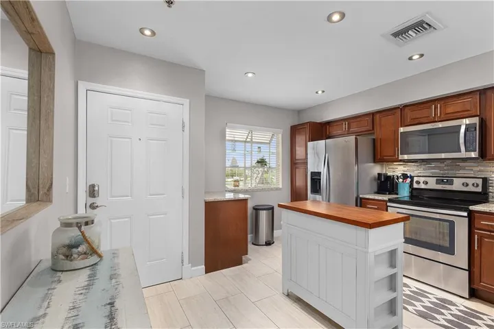 Kitchen featuring appliances with stainless steel finishes, wood counters, recessed lighting, backsplash, and brown cabinets