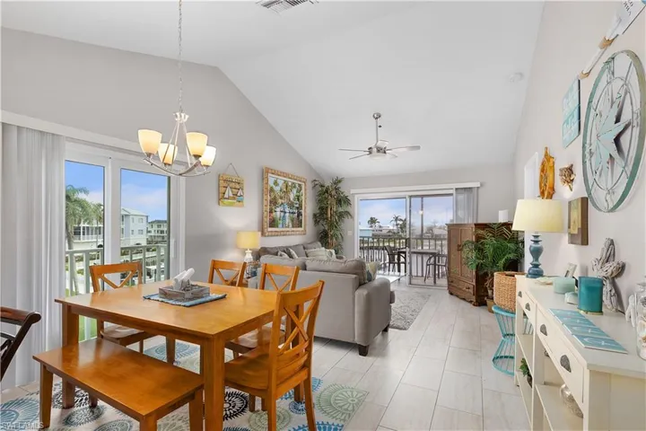 Dining space with a ceiling fan, high vaulted ceiling, and a chandelier
