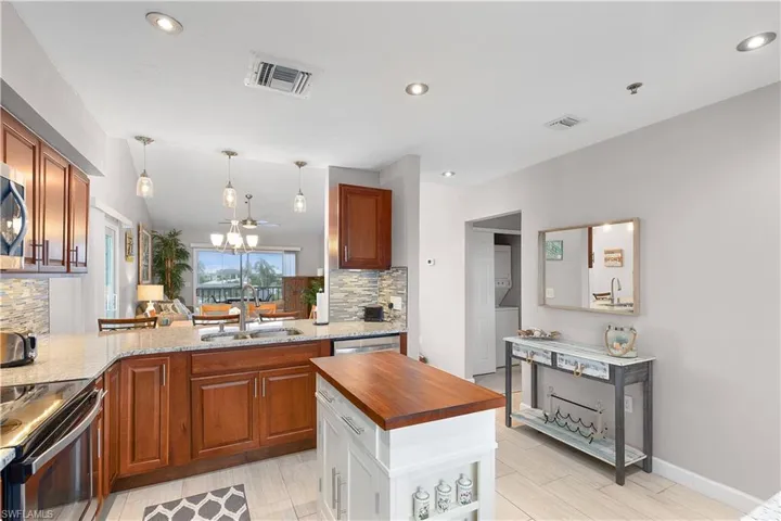 Kitchen with dark stone countertops, recessed lighting, stainless steel appliances, decorative backsplash, and decorative light fixtures
