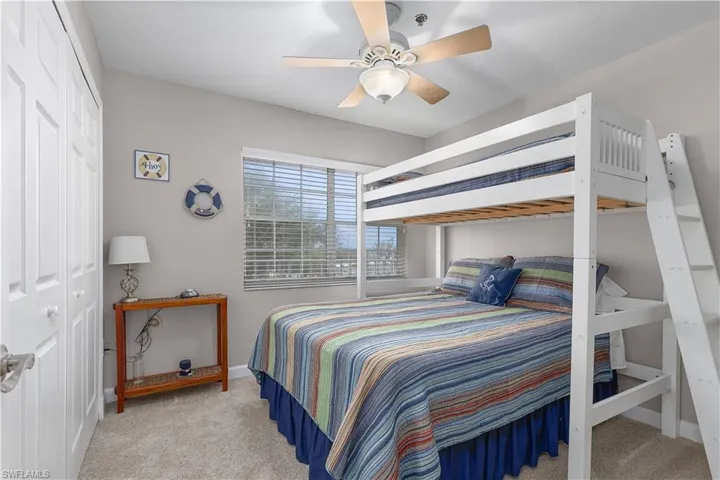 Bedroom with light colored carpet, ceiling fan, and a closet