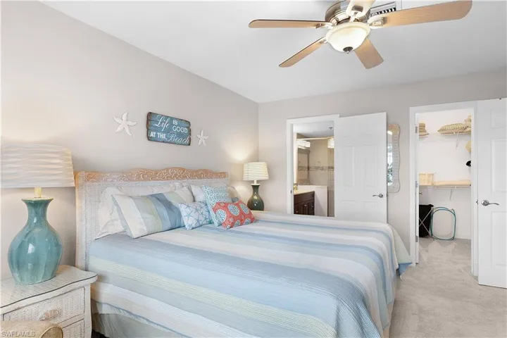Carpeted bedroom with a walk in closet, a ceiling fan, and connected bathroom