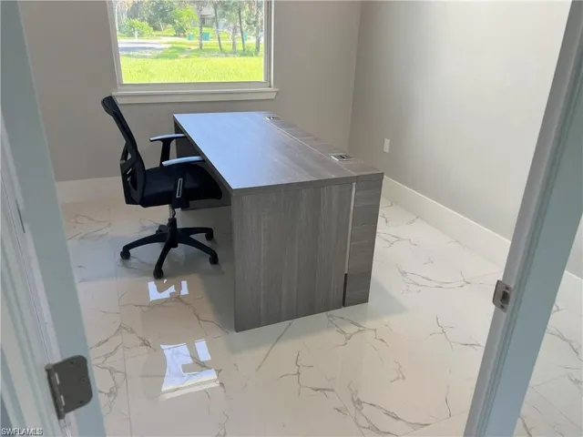 Bright room featuring large format white tile flooring with grey veining, neutral wall paint, and white baseboards