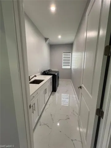 Bright laundry room featuring white shaker cabinetry, an integrated sink with a gooseneck faucet, and a light-toned countertop