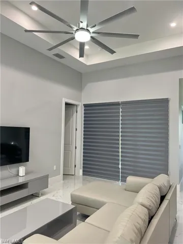 Living space featuring a tray ceiling with recessed lighting and a contemporary ceiling fan