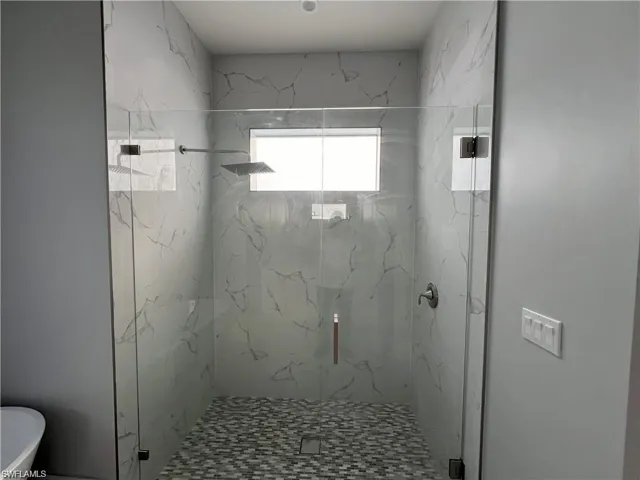 Spacious walk-in shower with clear glass enclosure and gray-veined tile walls