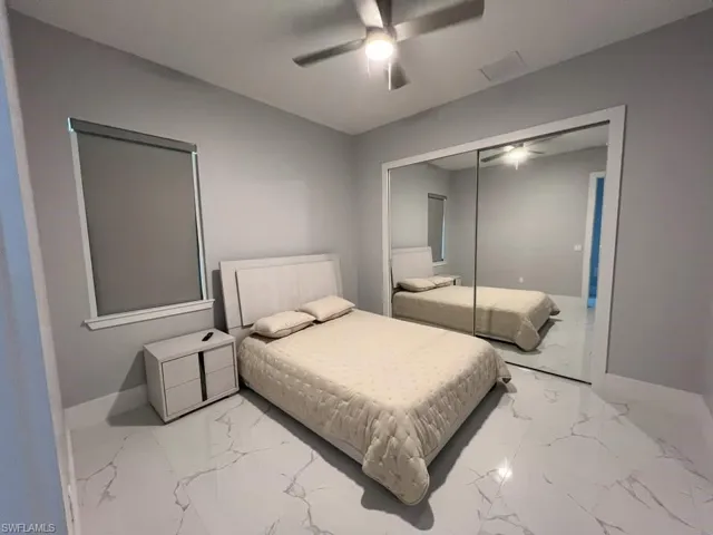 Bright room featuring large format tile flooring, a window with roller shade, and mirrored sliding closet doors
