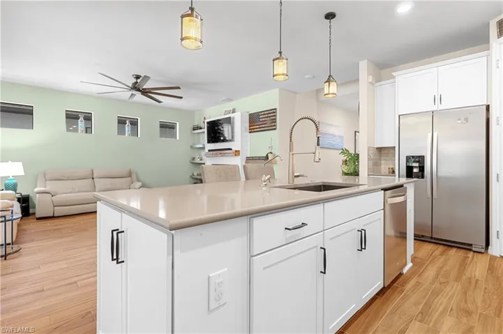 Kitchen featuring white cabinets, open floor plan, stainless steel appliances, and hanging light fixtures