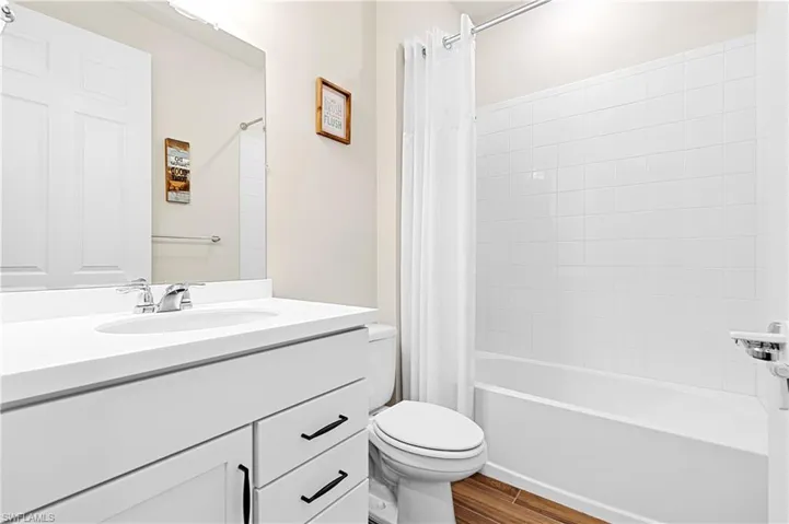 Full bathroom featuring vanity, shower / tub combo, and wood finish floors