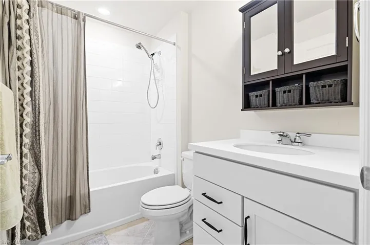 Bathroom featuring shower / bath combo with shower curtain, vanity, recessed lighting, and light tile patterned flooring