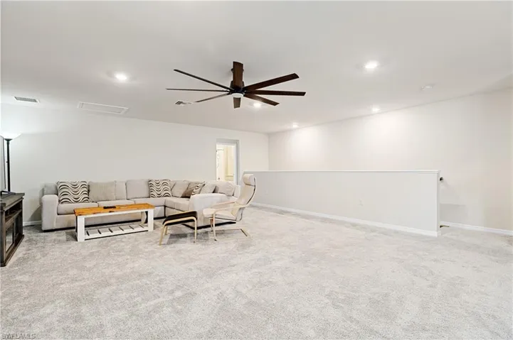 Living area featuring attic access, light carpet, recessed lighting, and a ceiling fan