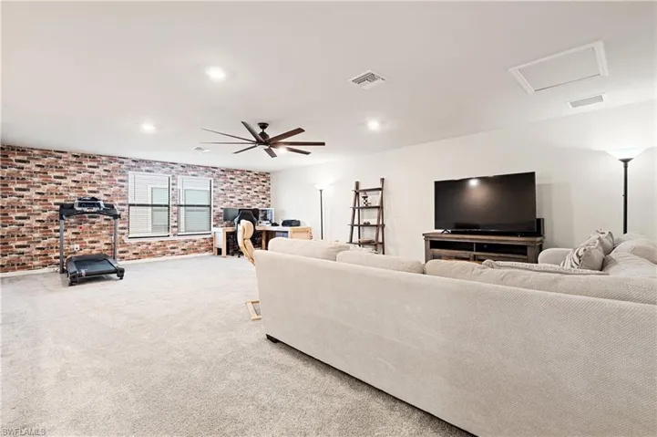 Living room with brick wall, a desk, attic access, carpet floors, and recessed lighting