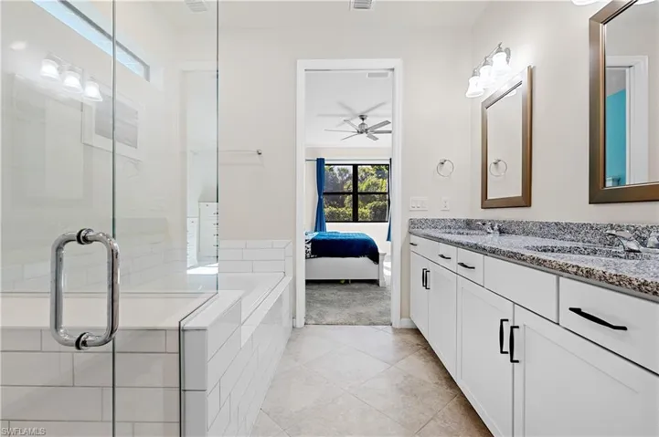 Full bath featuring connected bathroom, plenty of natural light, double vanity, and a shower stall