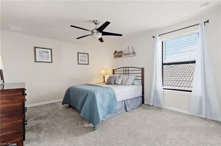 Carpeted bedroom with ceiling fan and baseboards