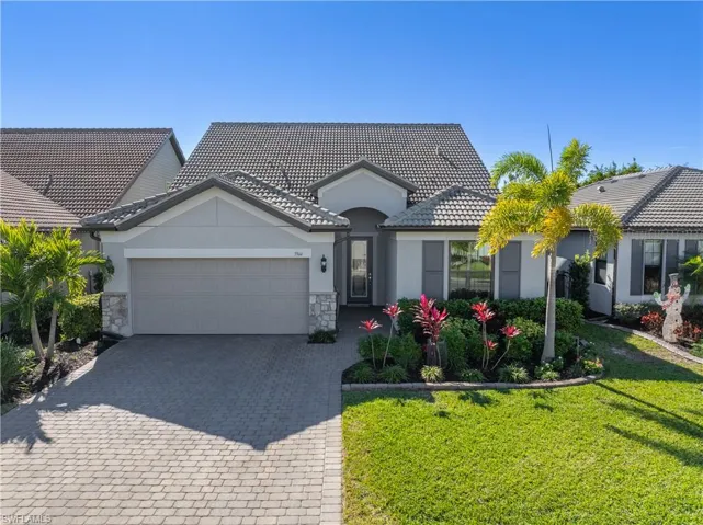 2 story home featuring stone siding, stucco siding, an attached garage, and decorative driveway