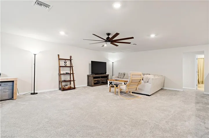 Living area with light carpet, ceiling fan, and recessed lighting