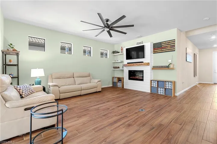 Living area featuring wood finish floors, a large fireplace, and ceiling fan